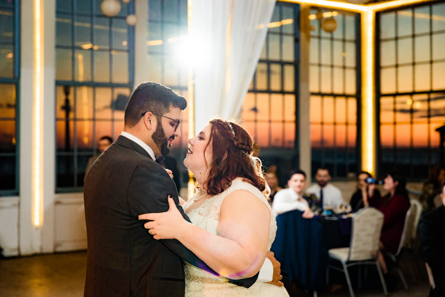 Bride and groom dancing first dance with sunset in windows on wedding day