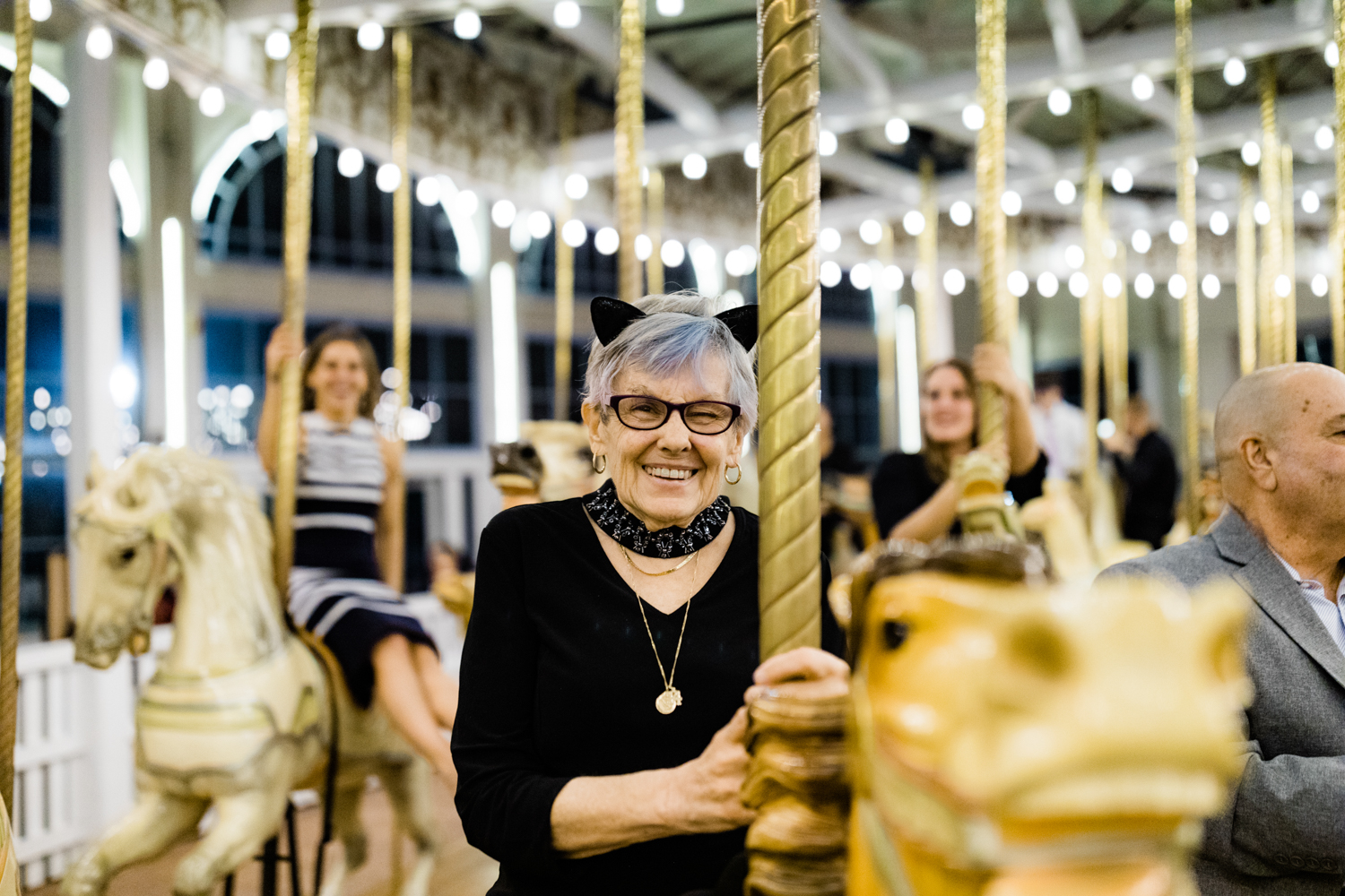 Grandmother smiling on wedding carousel wearing cat ears