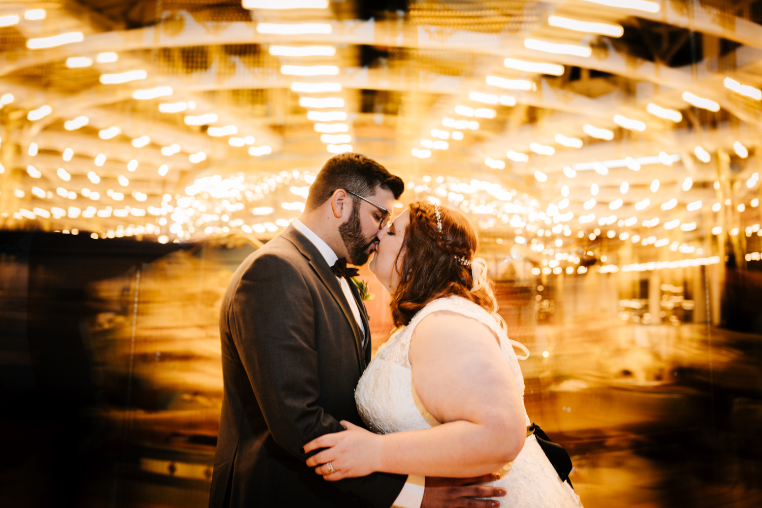 Bride and groom kissing in long exposure photo of carousel