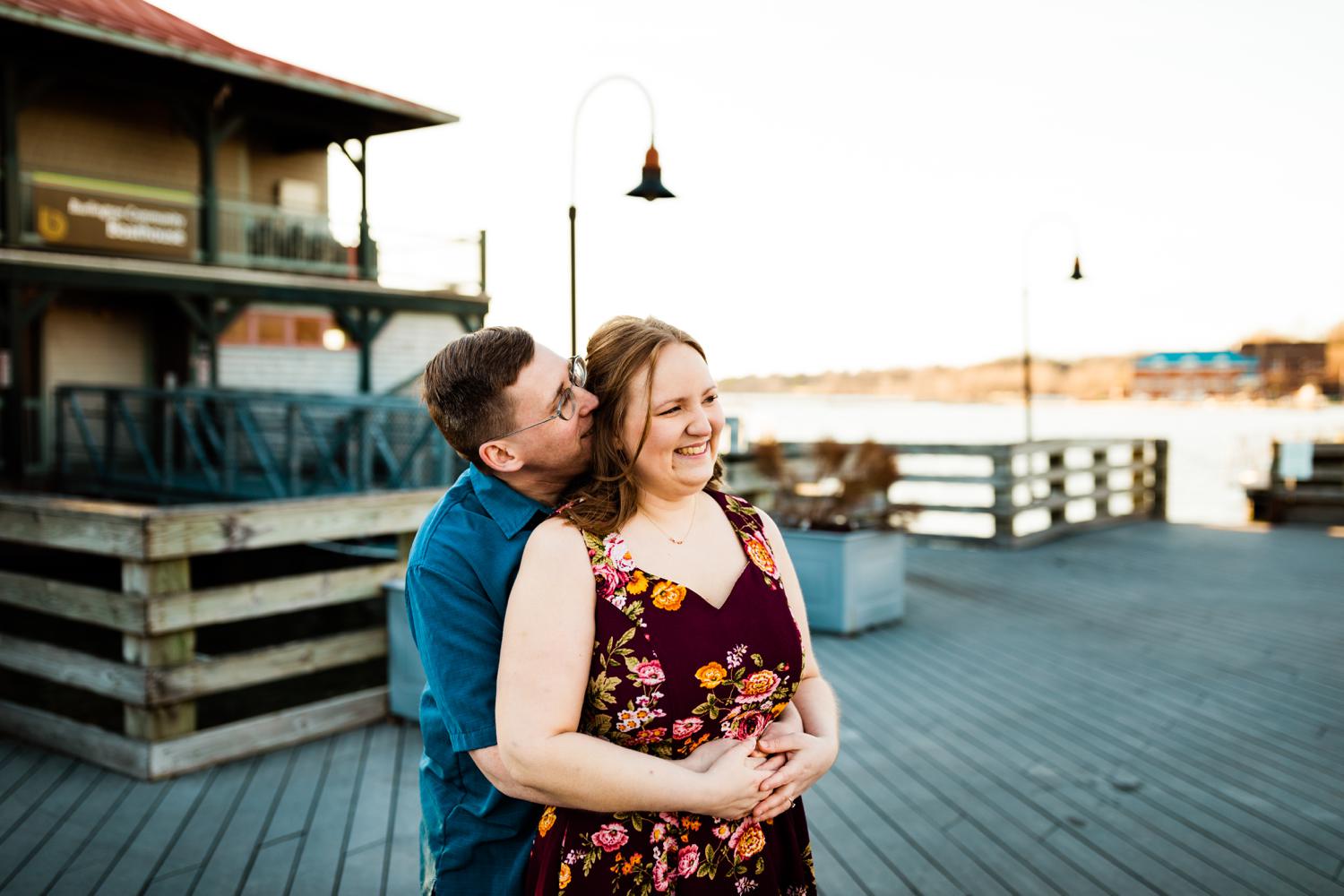 Engaged adventurous couple cuddling on boardwalk