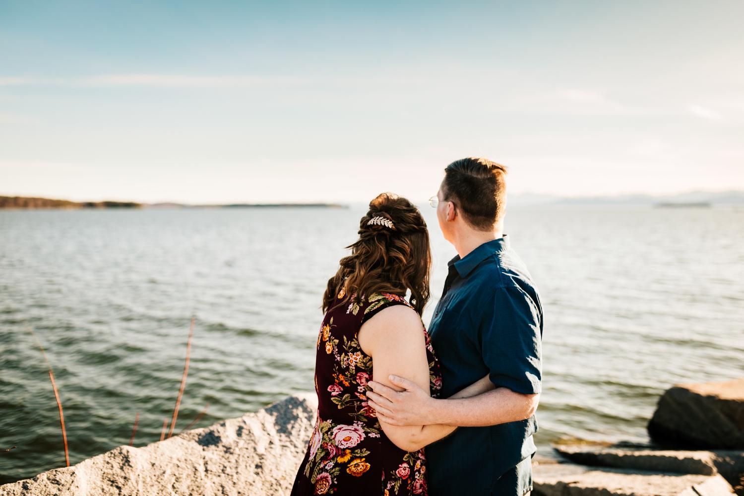 Fun couple looking at mountains and lake for engagement