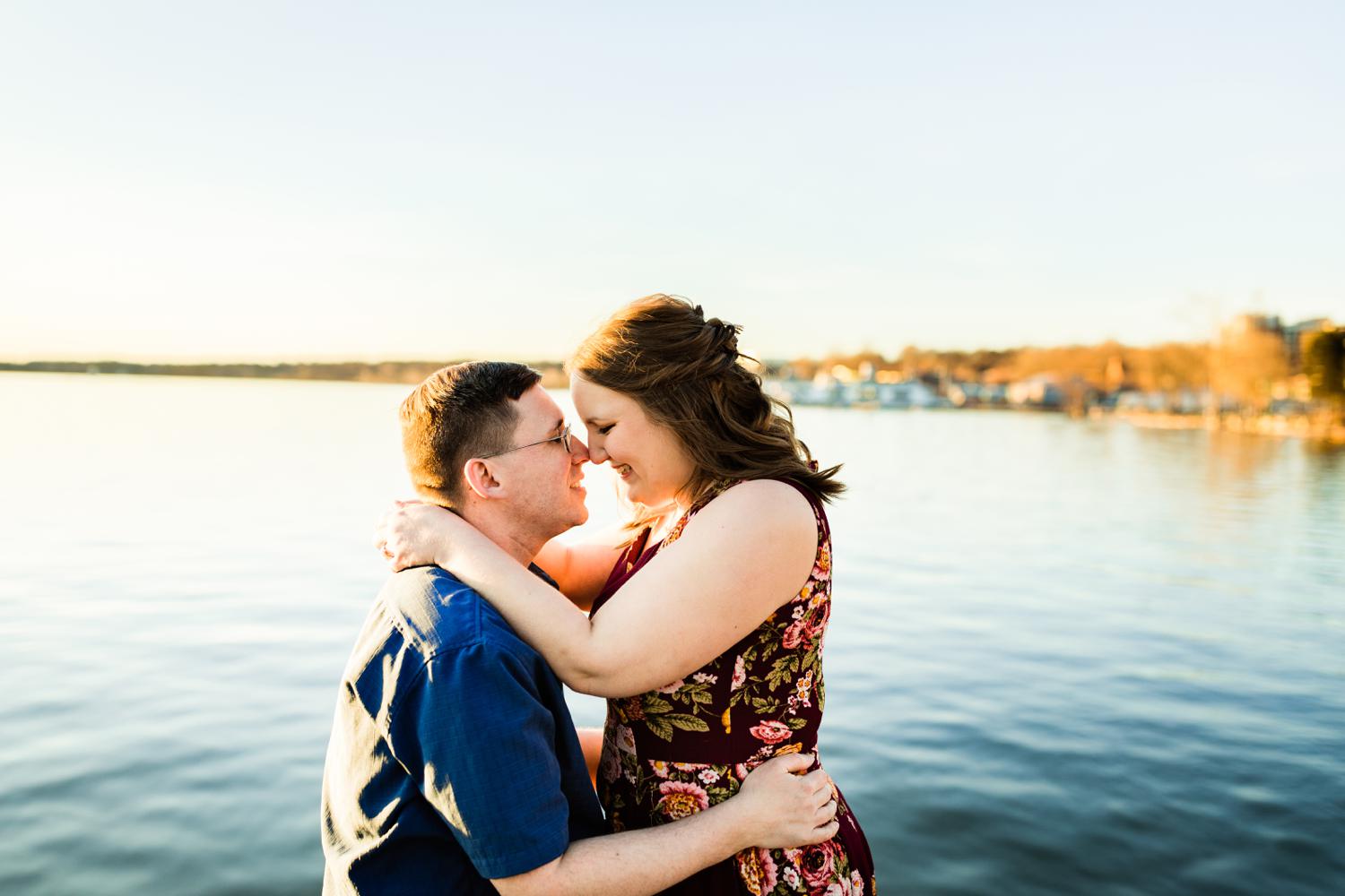 Engaged adventurous couple embracing at lake