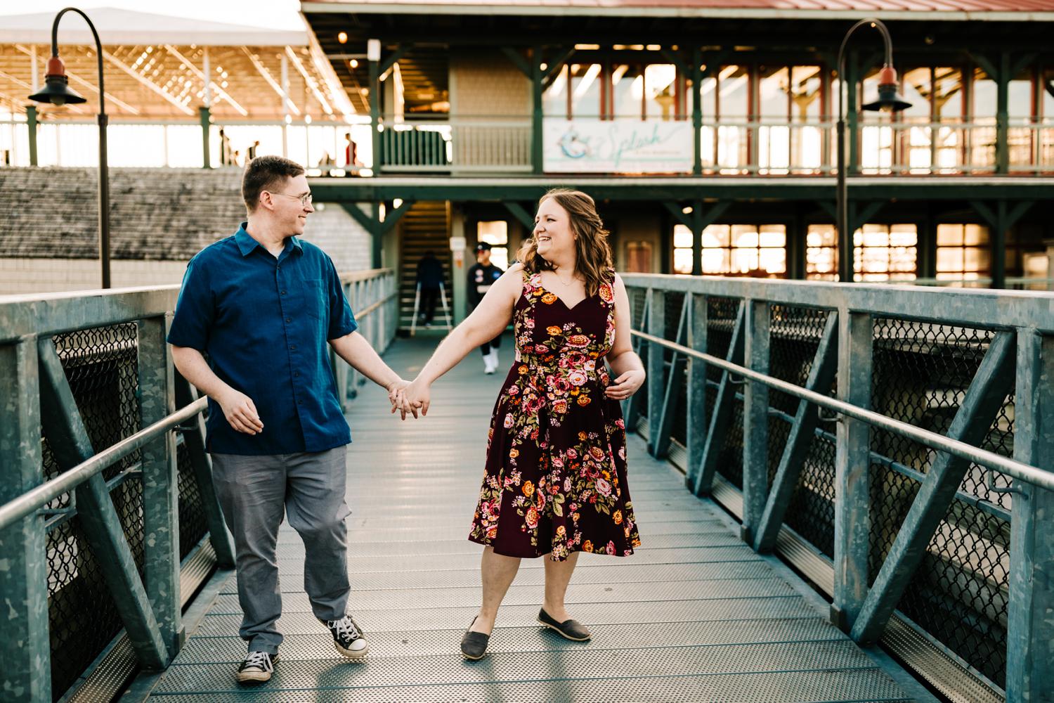 Engaged fun couple walking on boardwalk 
