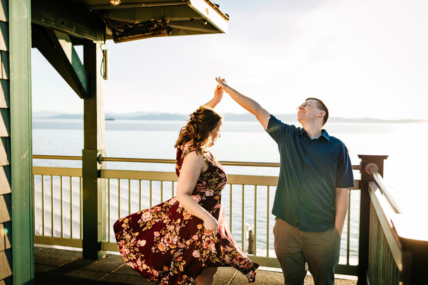 Couple dancing on boardwalk in front of mountains and lake