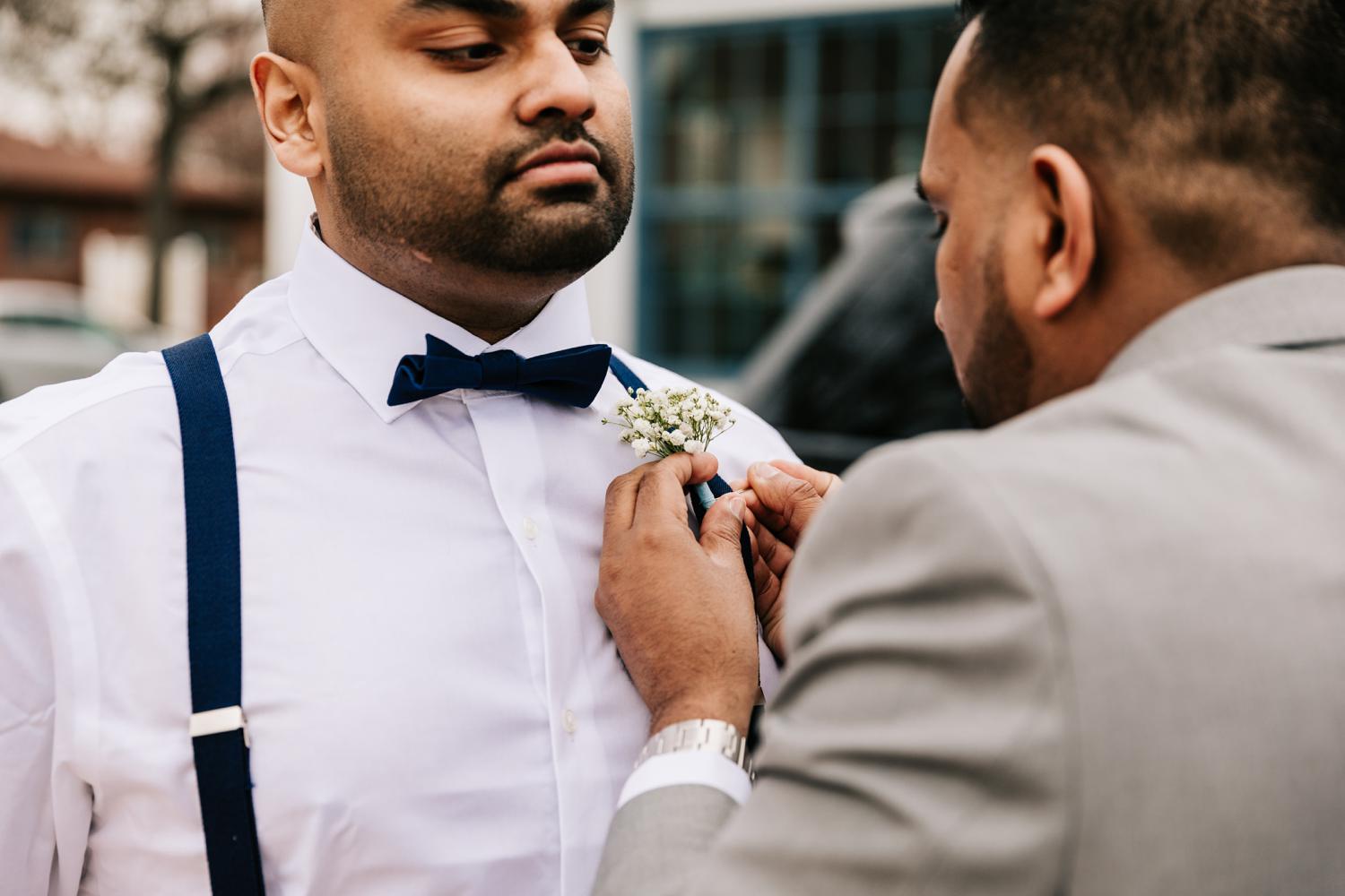 Groom pinning baby's breath flowers on best man