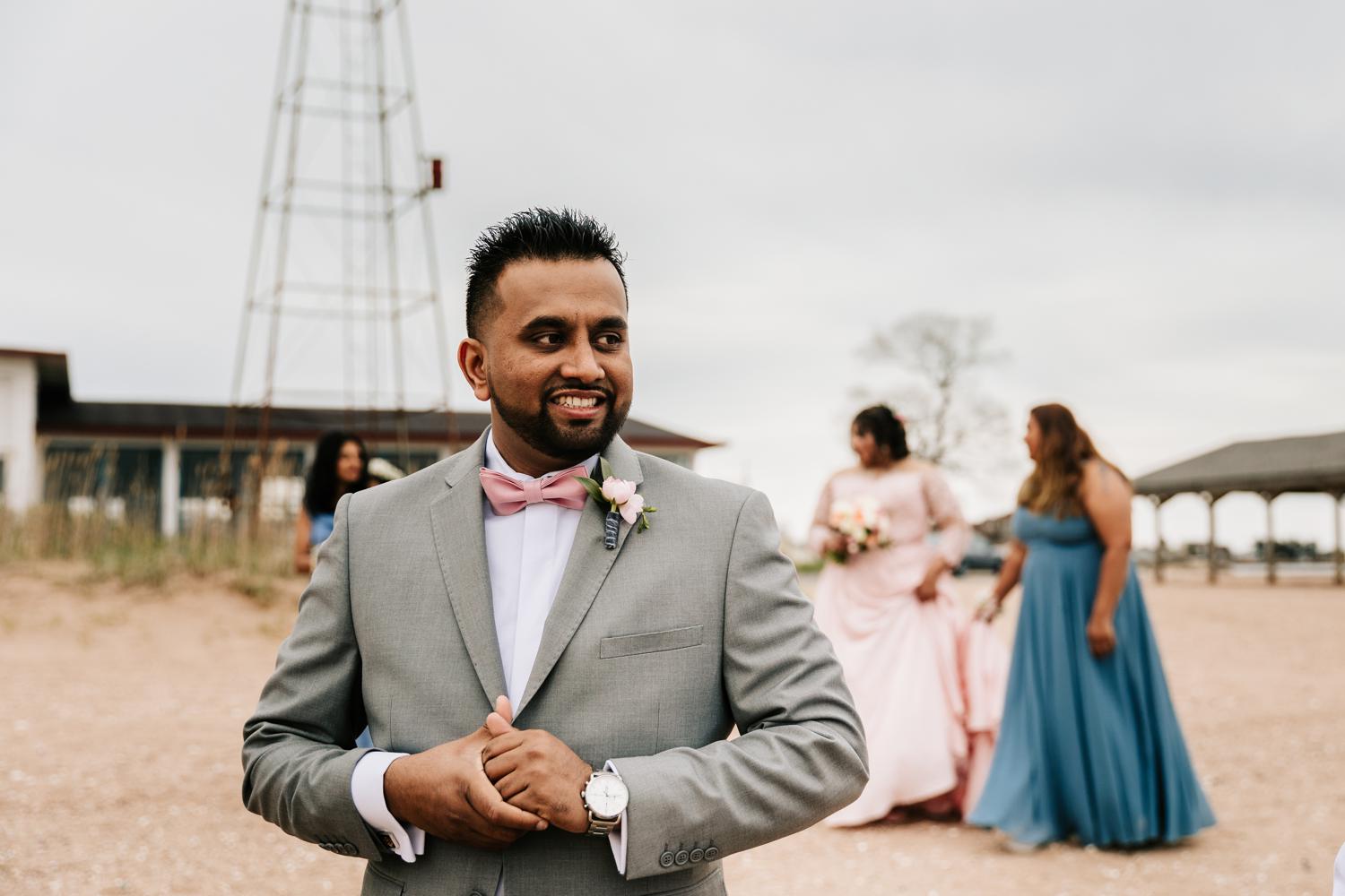 Groom during first look on beach wearing pink bowtie