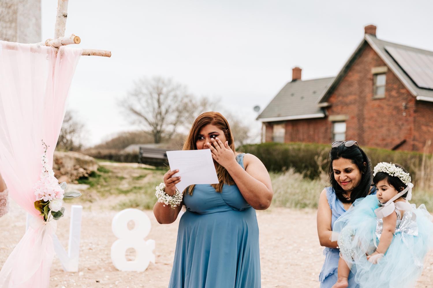 Bridesmaid giving speech during intimate beach wedding