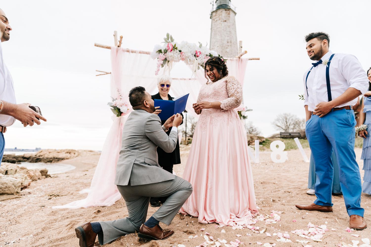 Groom exchanging rings with bride during beach wedding ceremony