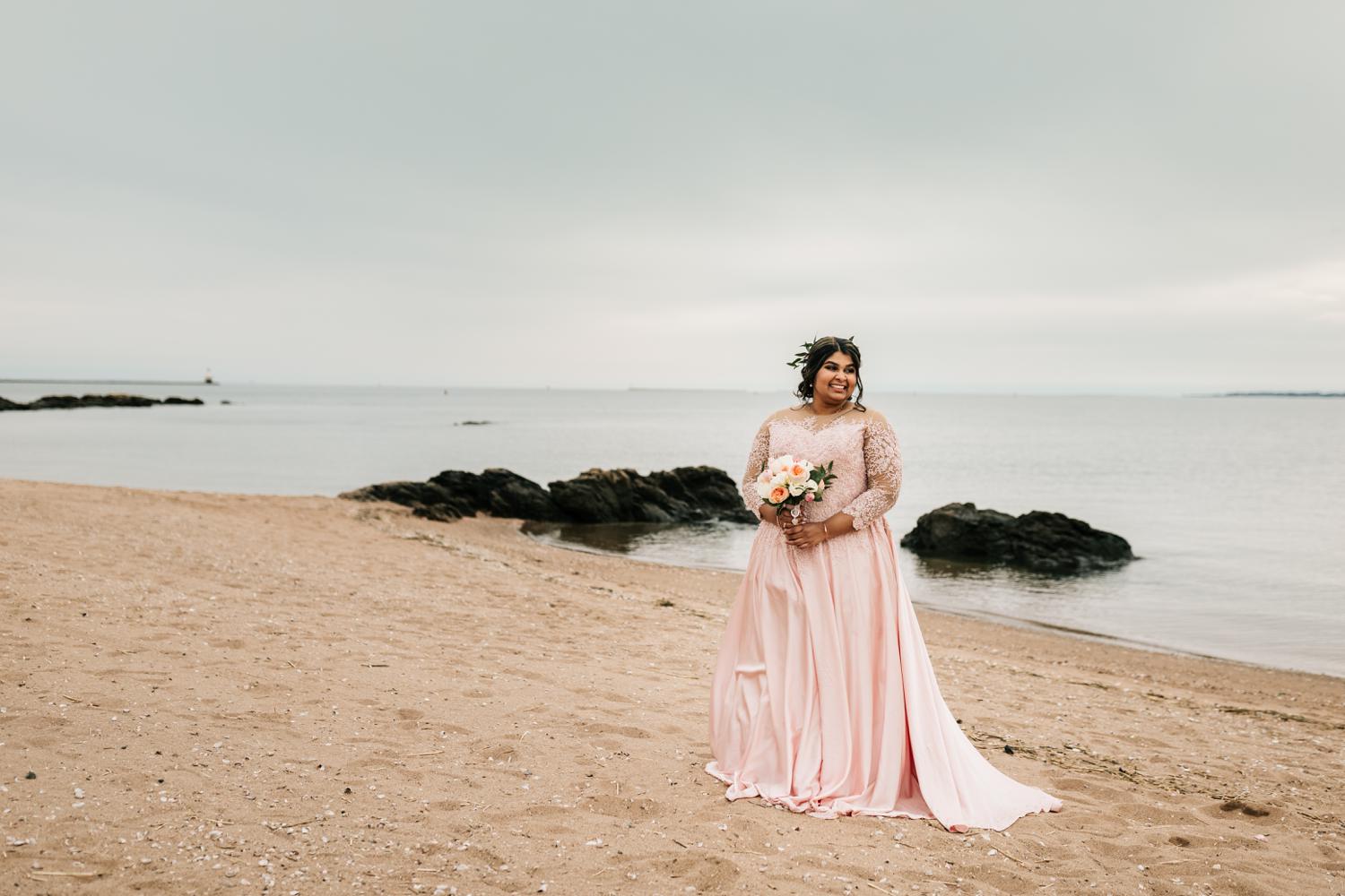 Bride in pink wedding dress on beach at sunset