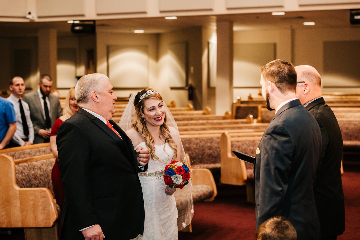 Father giving away bride looking at groom