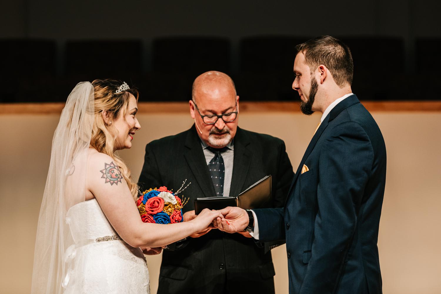 Tattooed bride and groom holding hands at altar