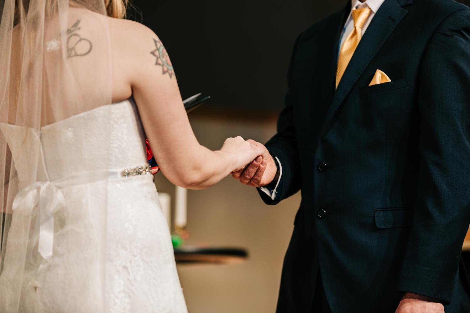 Tattooed bride and groom holding hands