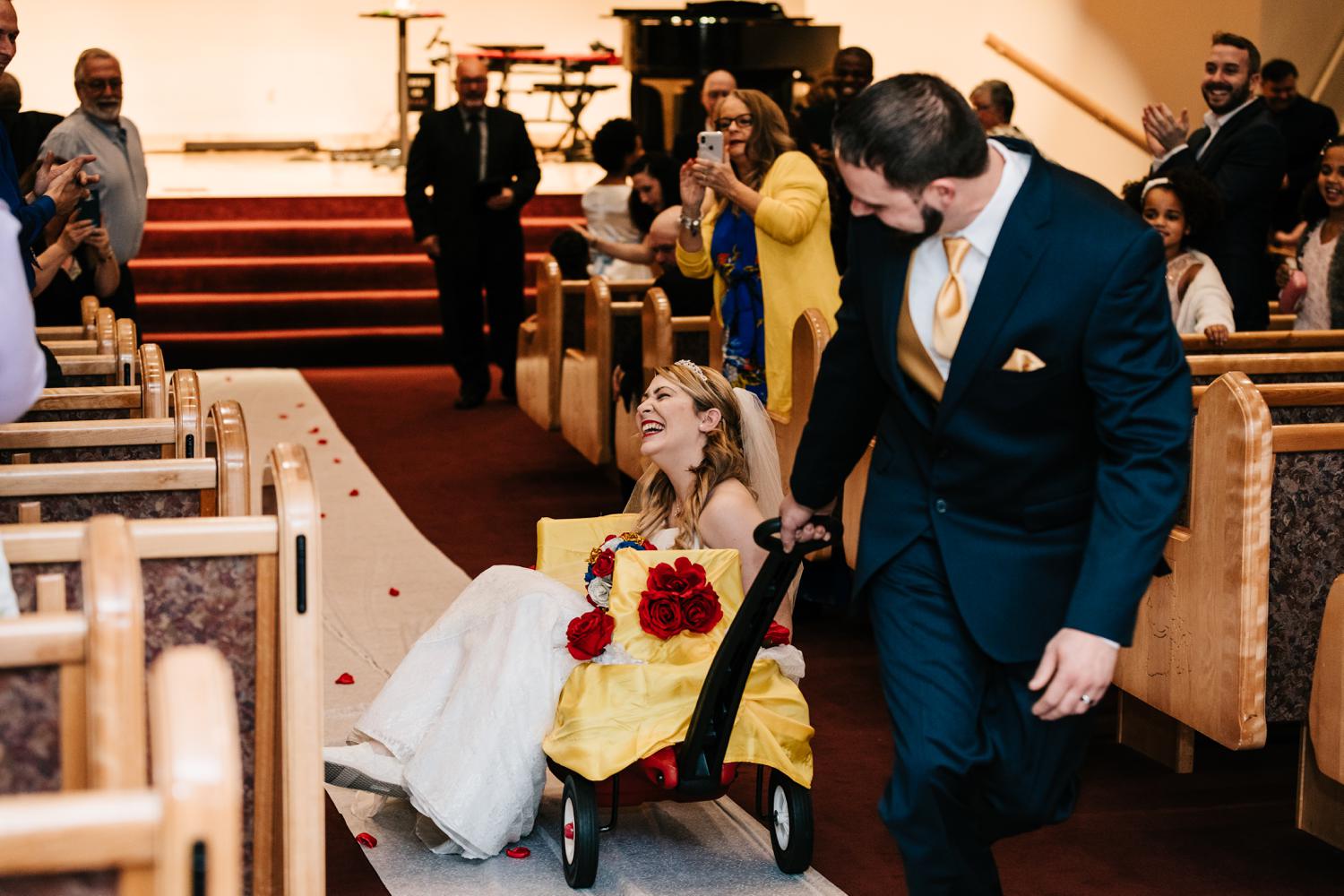 Groom pulling tattoed bride up aisle in wagon