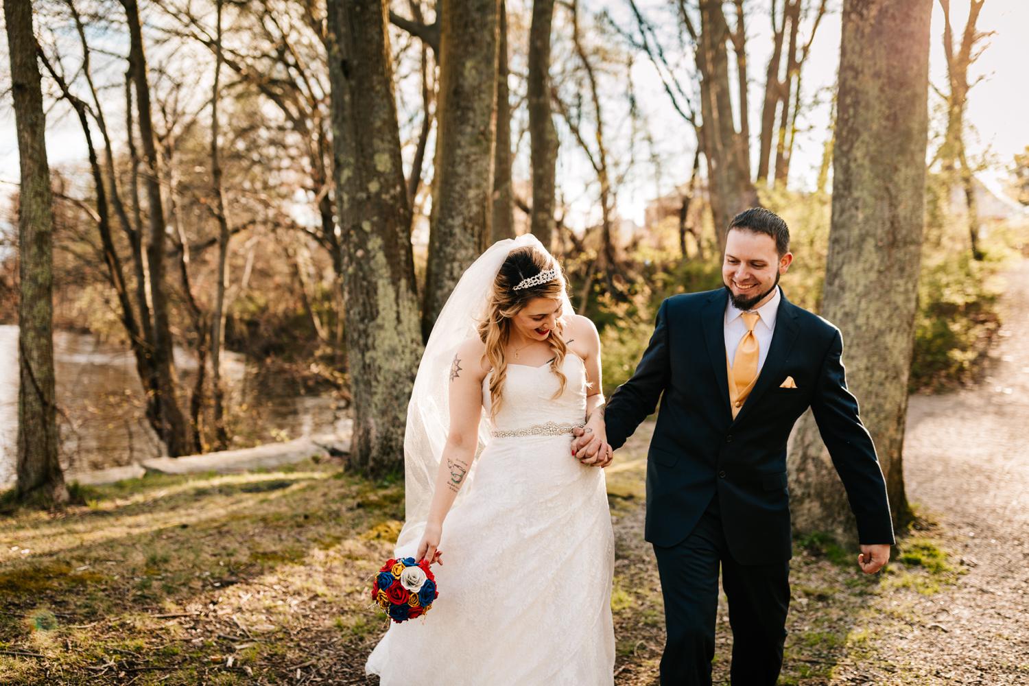 Bride and groom laughing and walking through woods