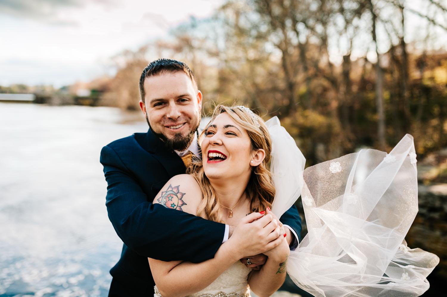 Tattooed bride and groom hugging on a windy day