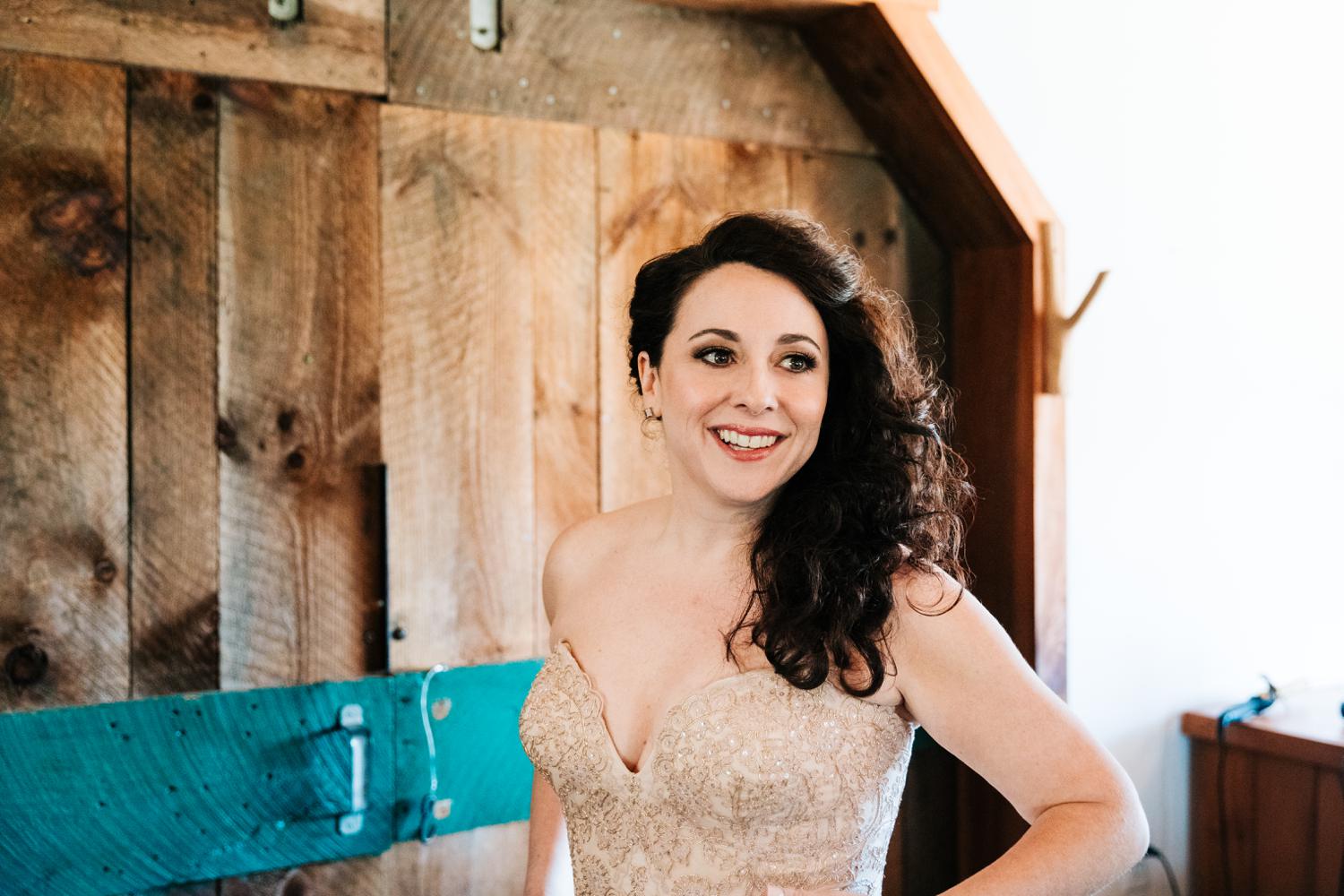 Bride smiling while putting on wedding dress in Santa Fe