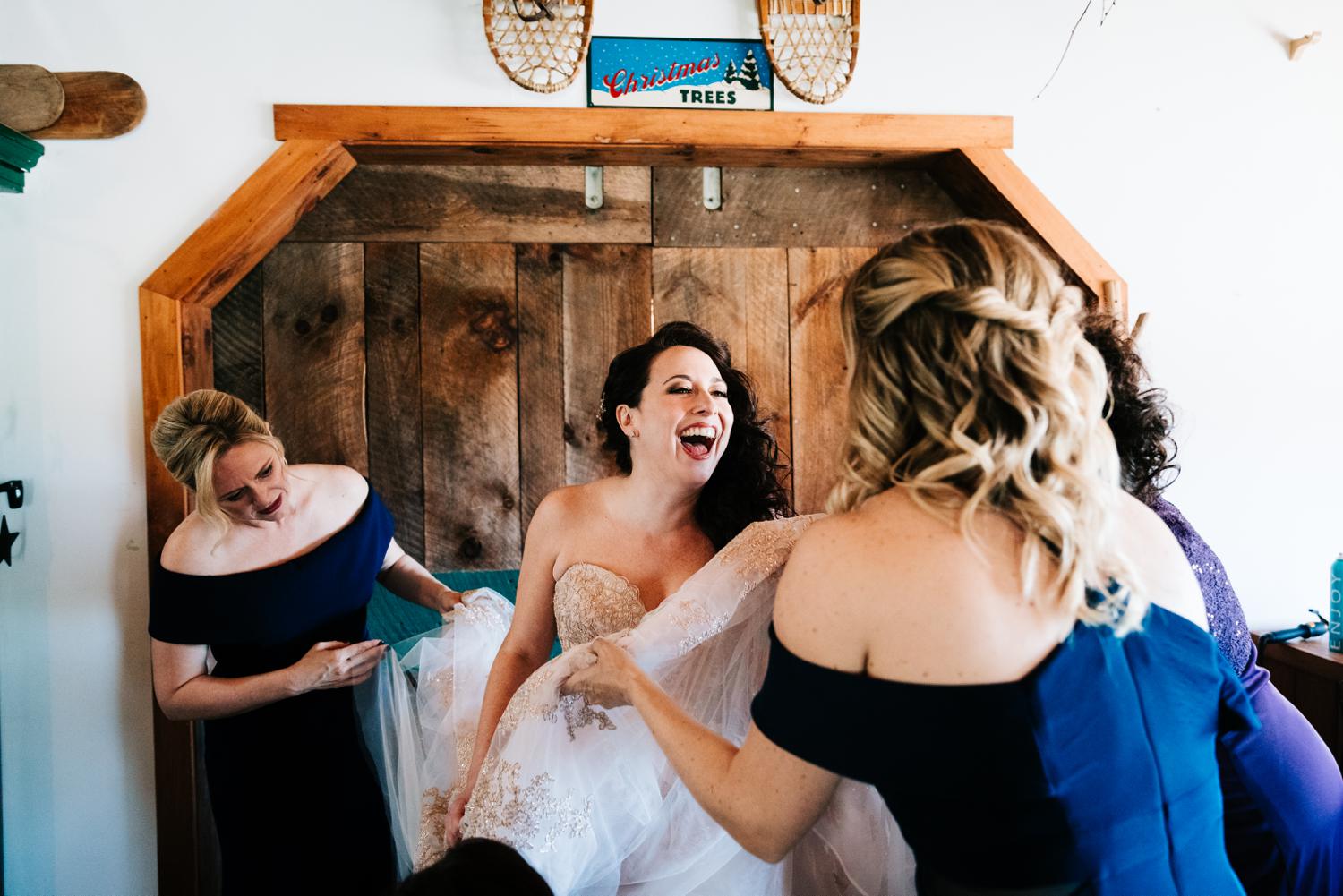 Bride laughing while putting on wedding dress in Albuquerque