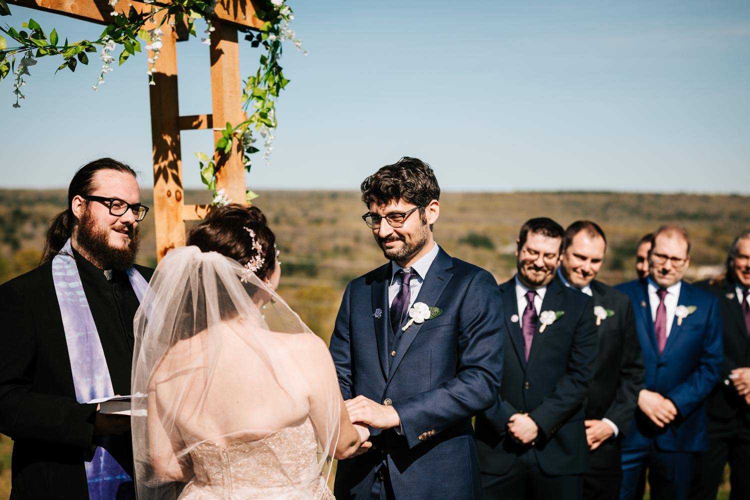 Groom looking at bride during ceremony under floral arch in New Mexico