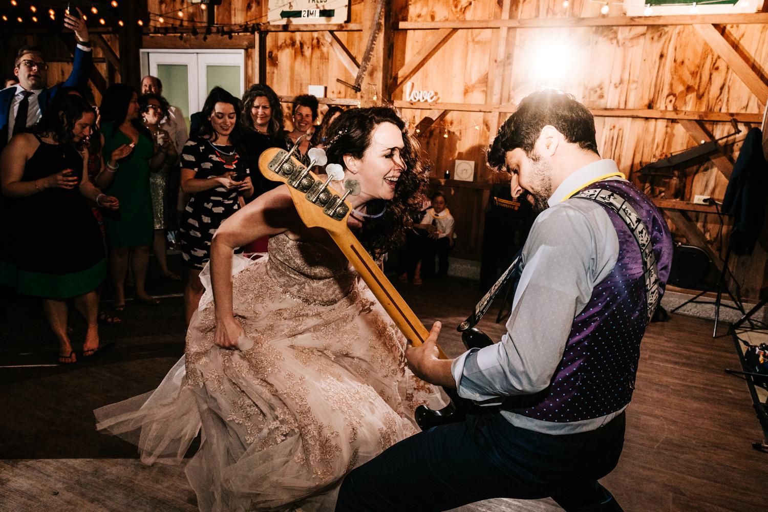 Bride and groom dancing and playing bass guitar in barn wedding in New Mexico