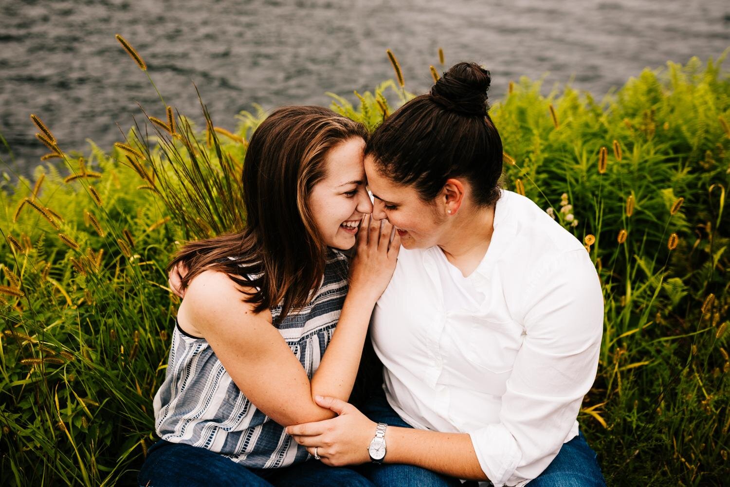 A cute LGBT couple sits together in the grass next to lake in New Mexico
