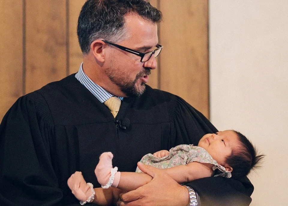 Rev. Michael Brown botezând un copil nou născut într-o familie de credincioși din Biserica Reformată Unită din San Diego.