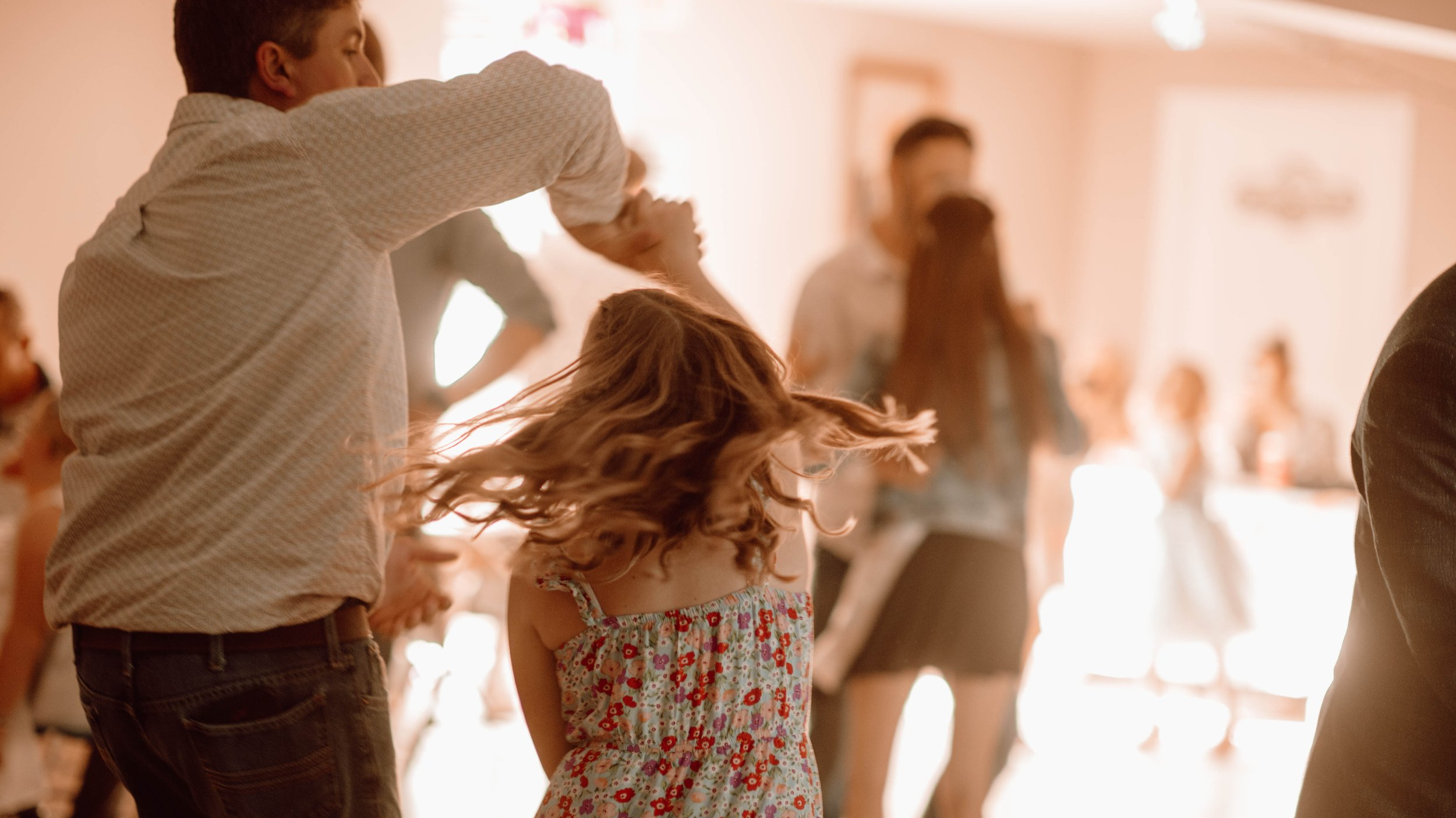 a man is holding his daughter's hand while spinning her around on the dance floor at the dundalk ag society's annual daddy daughter dance