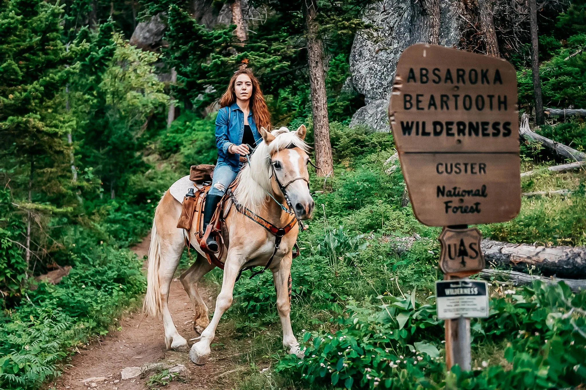 Portrait of woman trail riding her horse in the mountains during the summer. 