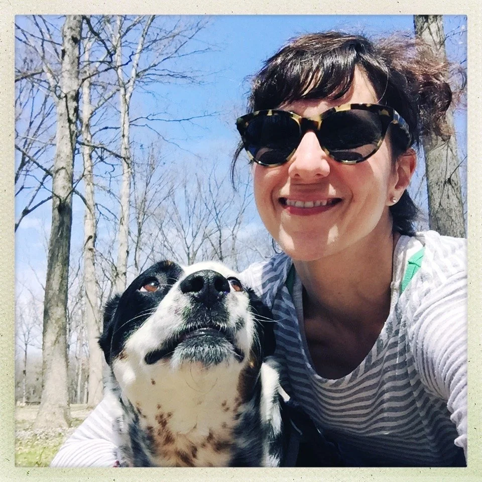 A black and white dog looking at the person who loves him most as they pose for a photo together on a sunny spring day.