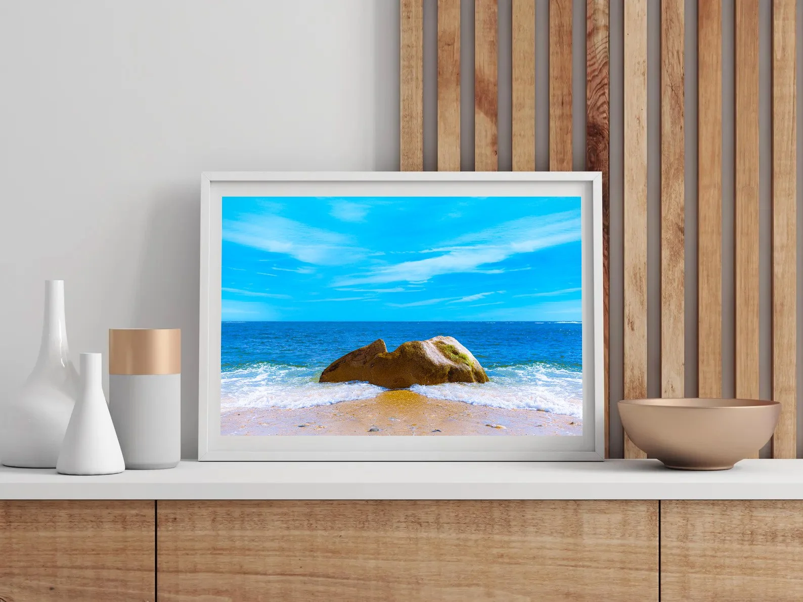Fine art photograph of a large golden-brown boulder surrounded by white Atlantic waves on a sandy Long Island beach beneath a vivid blue sky.