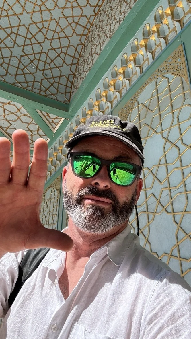 Charles Lindsay in Uzbekistan, wearing green reflective glasses against geometric architectural ornament.