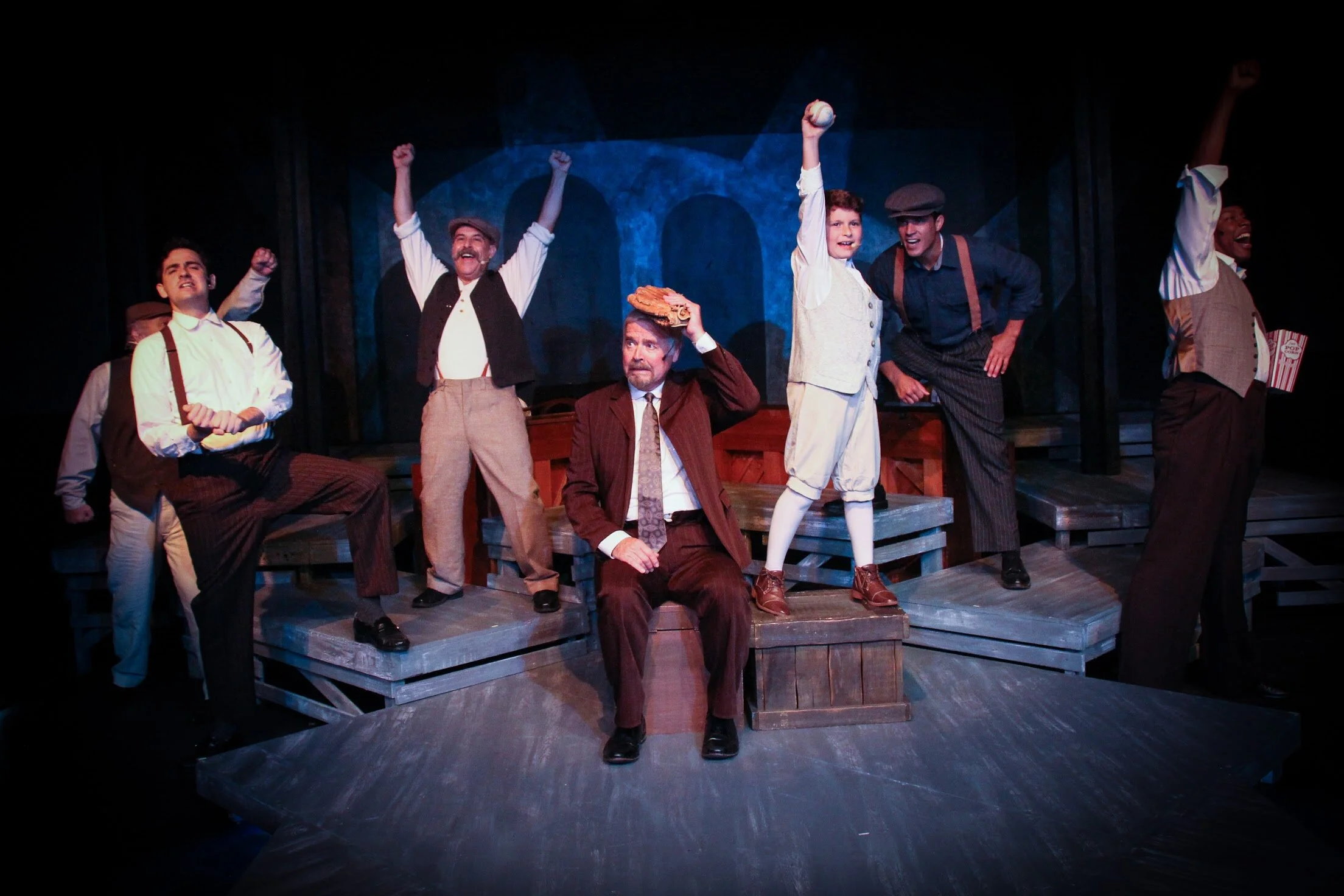 Father (Dennis Holland), seated, and his son (Ari Zimmer) and the male cast of Ragtime