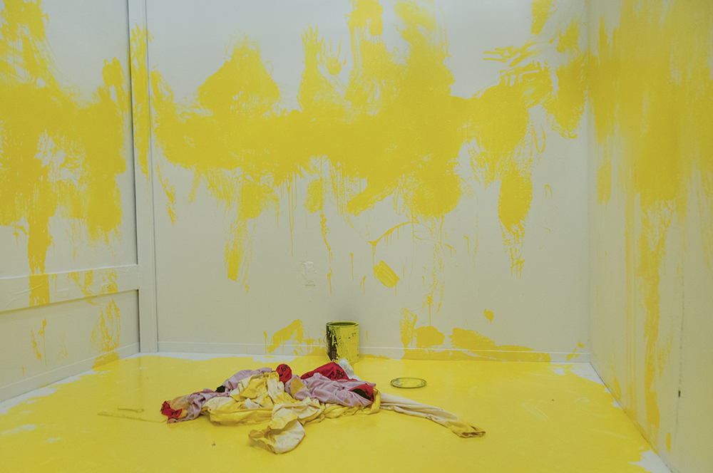Marking. Multimedia installation: yellow paint, oriental kimono, Coverall, googles, face mask, paint can, paint opener, documented performance, and television sets. 96x125x96 inches. Installation view.