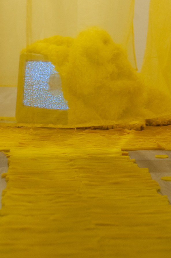 Is this | This is… Multimedia installation: yellow curtains, old television, copy of Native Speaker by Chang Rae Lee, wig, 20 packs of rectangle dan moo ji, 5 packs of circle dan moo ji, print, shag rug, scrabble letters. 120” x 240” x 240” Installation view.