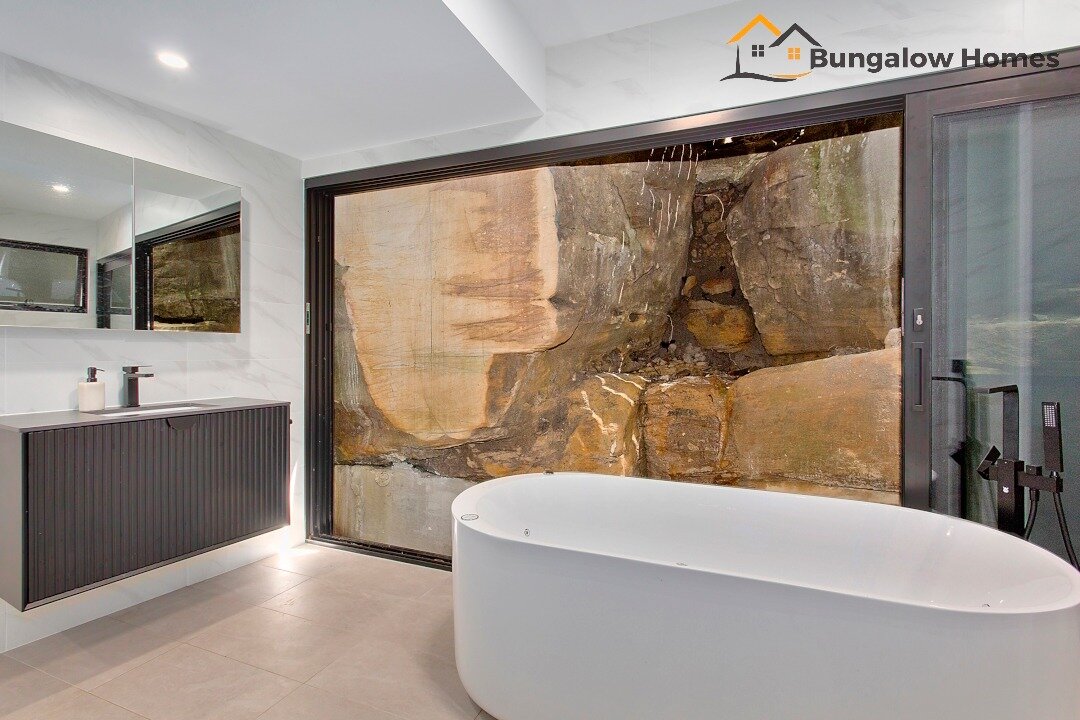 What's the view like from your bathroom?

This Granny Flat features the natural landscape differently, with a modern, luxurious bathroom opening up to the natural sandstone rock face. 
This stunning feature is a testament to the way we collaborate wi