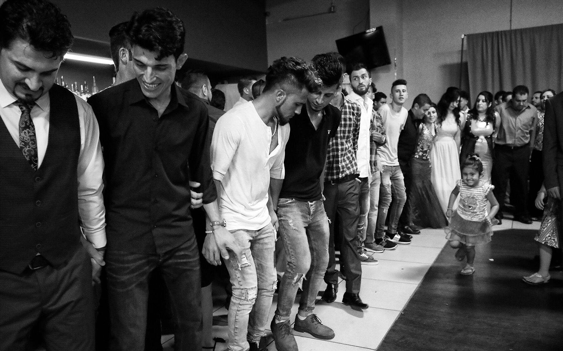  Women wear traditional dresses and everyone joins in a shoulder-shaking shingaly dance on a Yazidi couple’s wedding day. Lincoln, Nebraska, 2017. 