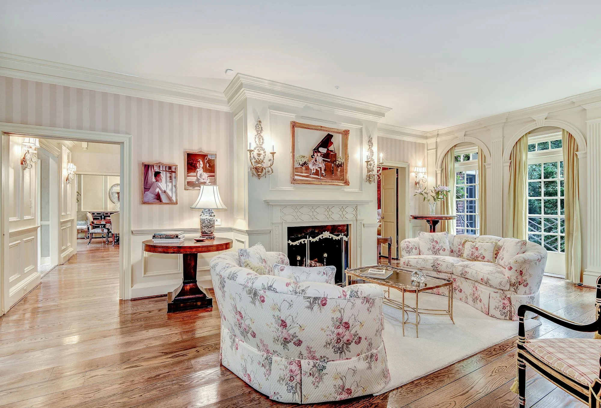 The elegantly appointed Living Room features a beautiful fireplace, custom millwork and access to a brick terrace overlooking the landscaped gardens, swimming pool and spa