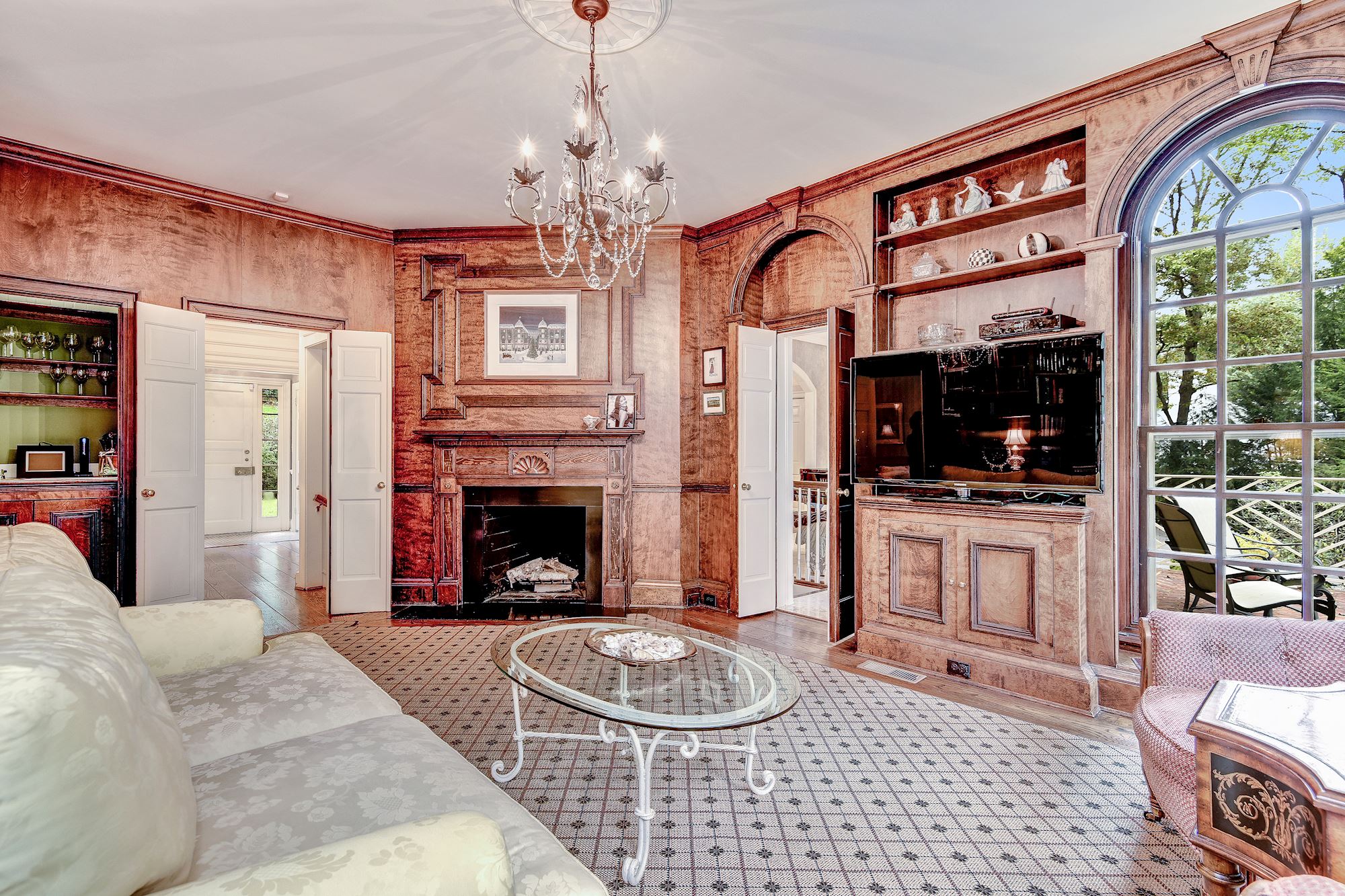 The paneled Library with wood-burning fireplace and wet bar is the perfect place to relax. It opens to a brick terrace