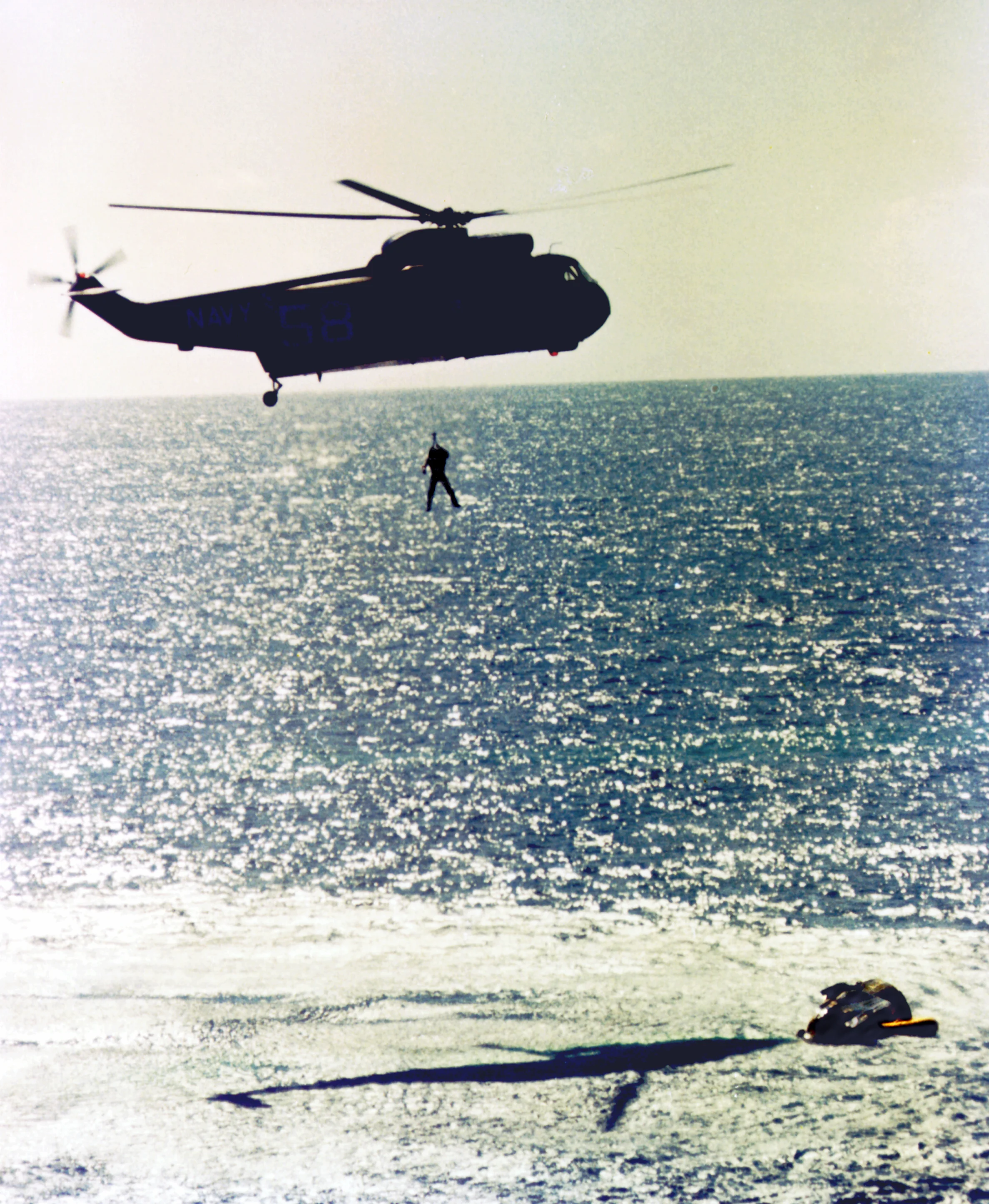 Gordon Cooper is hoisted into a helicopter before being flown to recovery ship, USS Lake Champlain