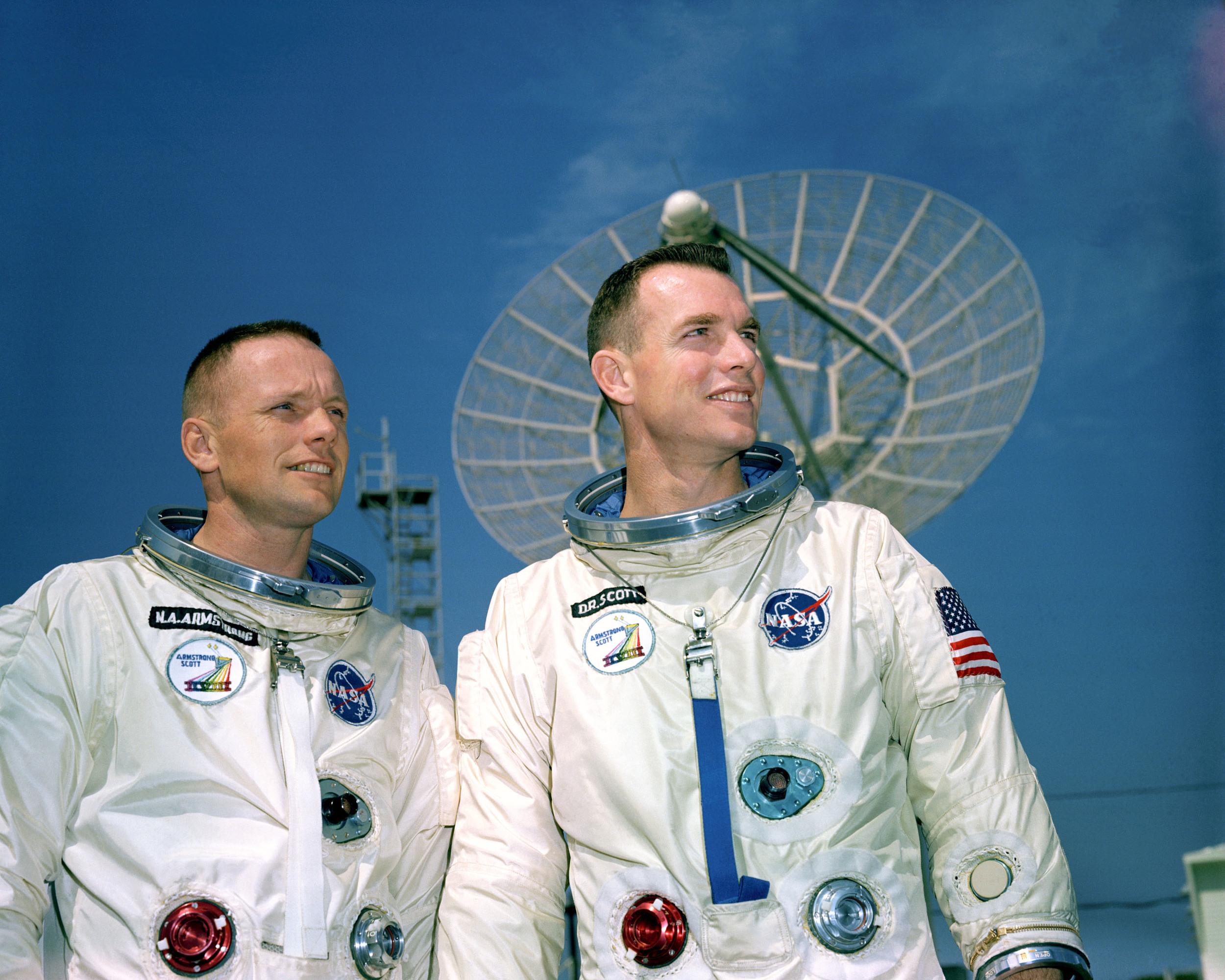 11 March 1966 - Astronauts Neil A. Armstrong (left), command pilot, and David R. Scott, pilot, the Gemini-8 prime crew, during a photo session outside the Kennedy Space Center (KSC) Mission Control Center. They are standing in front of a radar dish. Photo credit: NASA