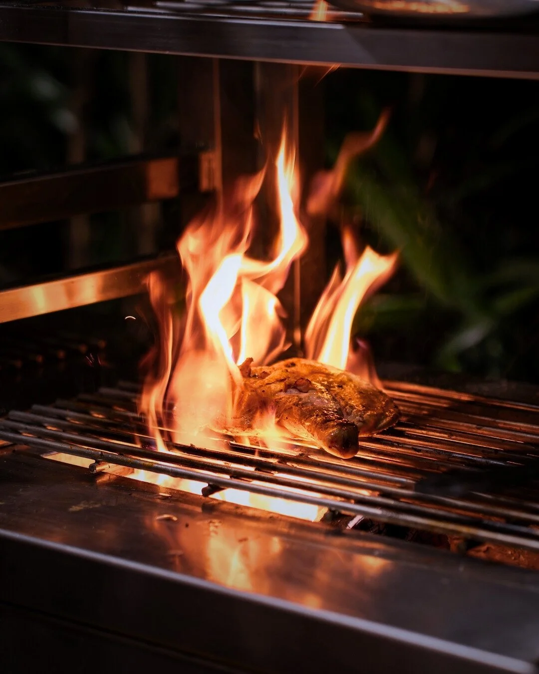 Meat grilling on a barbecue with flames and heat at Copper, restaurant in Ubud