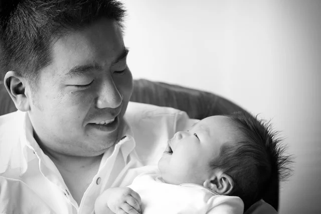Hong Kong father holding newborn baby laughing