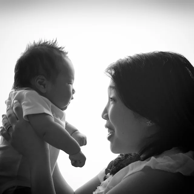 black and white photo of newborn baby boy and mother facing each other