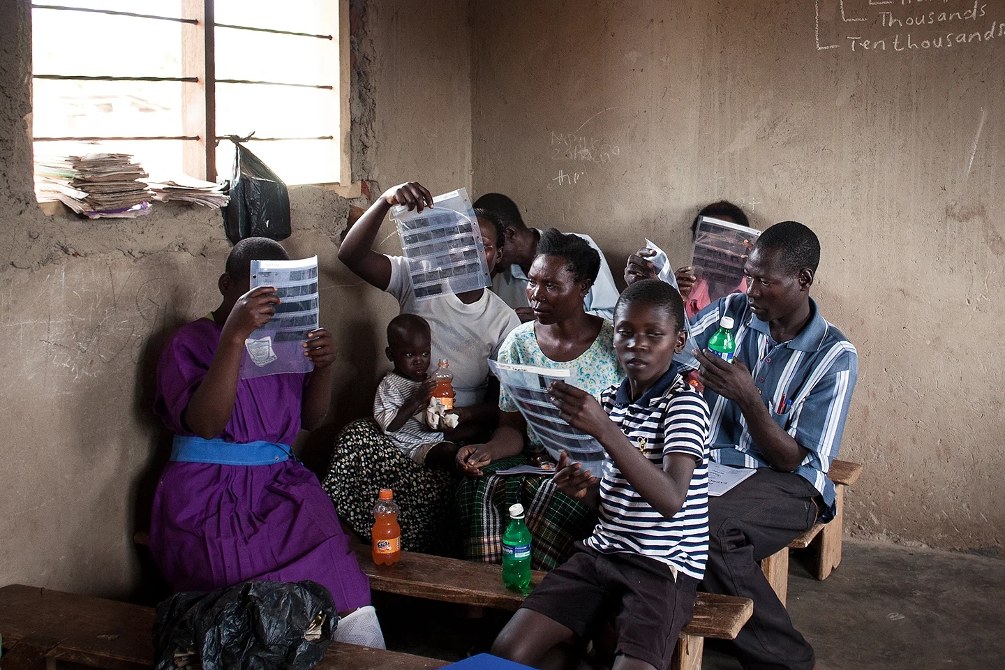 The WPC would gather in the Junior School classrooms designed and managed by their local CBO (community based organization) BESO Foundation. Here the group is looking at their negatives, which they just hand developed for their first time. The magic of film nestles in this important moment. 