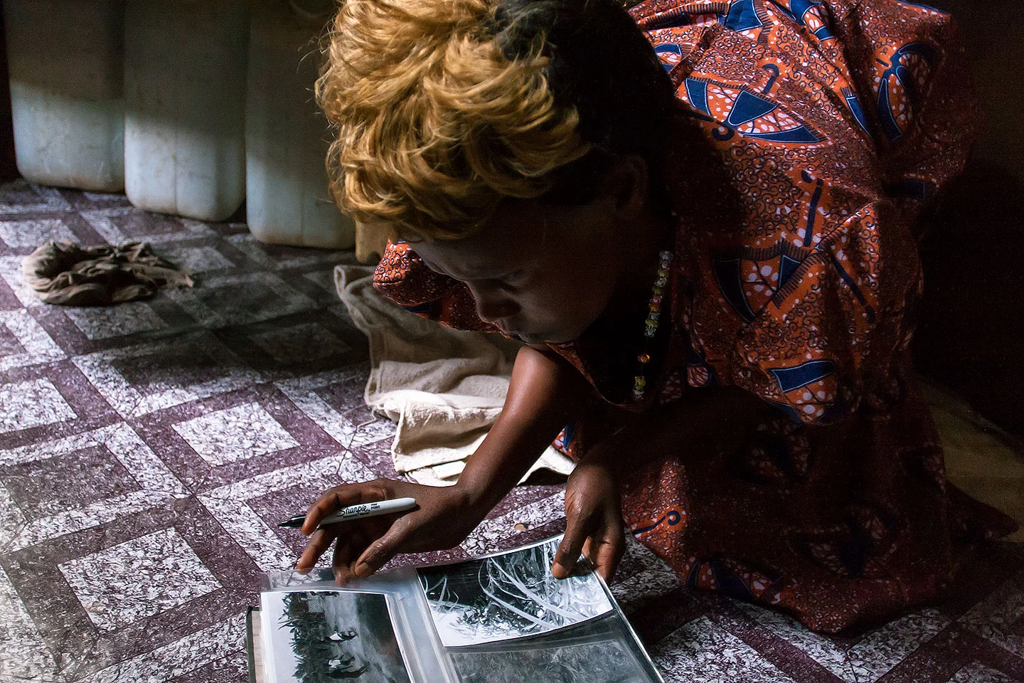 WPC member Anyango Florence looking at her photographs in her home and selecting which ones she wishes to exhibit in the permanent collection. 