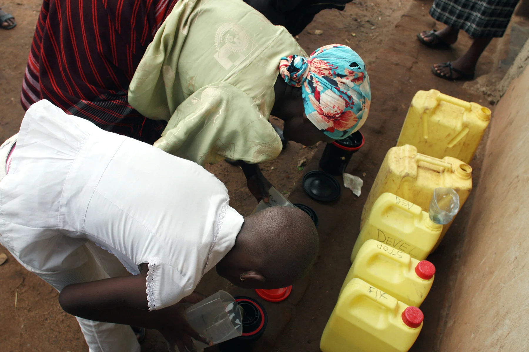 We used "jerry cans" (empty containers that once held cooking oil) to contain the chemical solutions needed to develop film (developer, stop, fixer and permawash). Here you see members of the WPC pouring the chemical washes into their light-safe film developing tanks for their first time. 