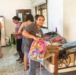 Stuffing backpacks with pens, notebooks, erasers, rulers, and more