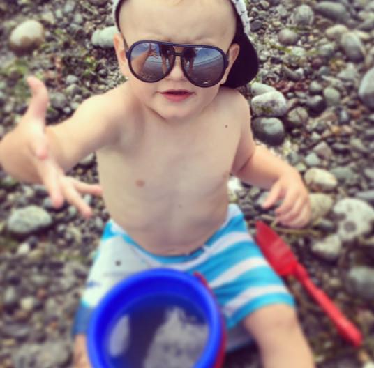 Stand over them while they play. Hudson was digging in the sand (and rocks) here and I just kept snapping away. After some editing it actually turned out to be a cute action shot of him showing me how dirty his hand was. Plus, how cool is the sunnies reflection? That was a total accident!