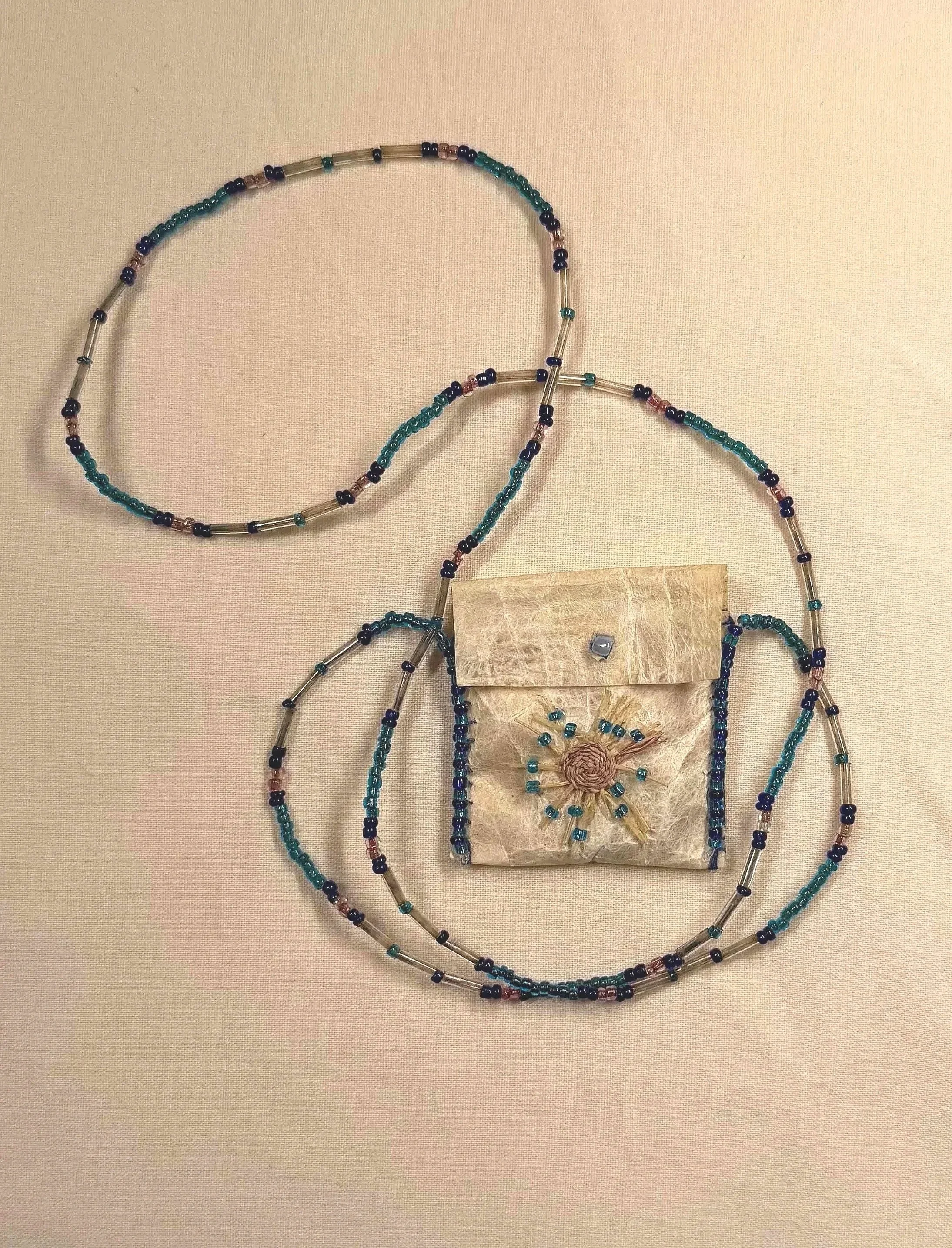 Northern fur seal gut bag, adorned with glass beads and raffia basket start, 38cm x 4.5cm