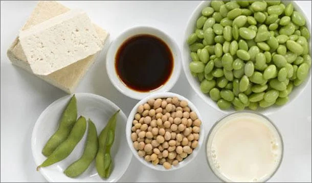 Table with multiple different soy products: tofu, edamame, soymilk, soy sauce, dried soybeans and fresh soybeans