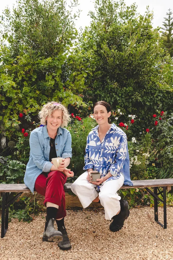 Avant Gardeners, Madeleine Gasparinatos and Emily Allen, sitting on a bench in the garden.